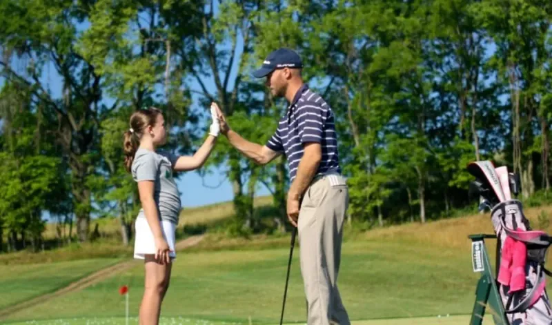 Jaime high-fiving a junior golfer on the range