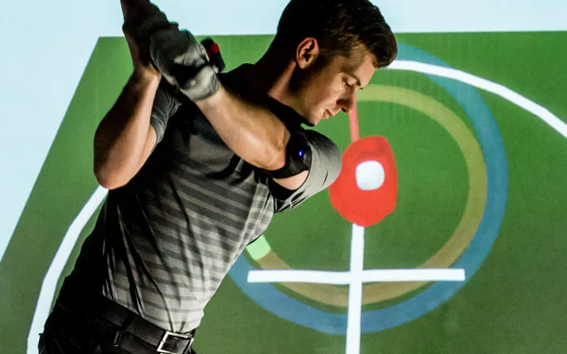 A golfer wearing K-Vest motion sensors, with the swing shown on screen